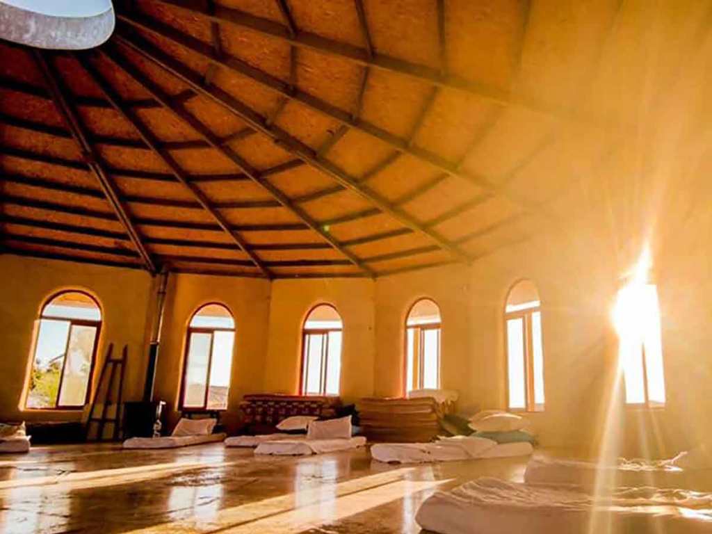 האולם המרכזי ב״זמן מדבר״ מזרנים פרוסים לשינה. זריחה מבעד לחלונות