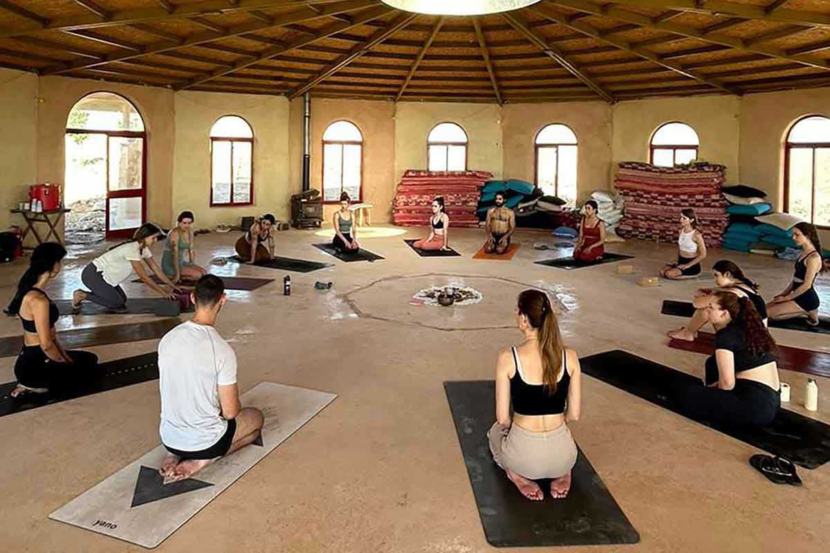 מתאמנים ביוגה על מחצלות באולם המרכזי של ״זמן מדבר״